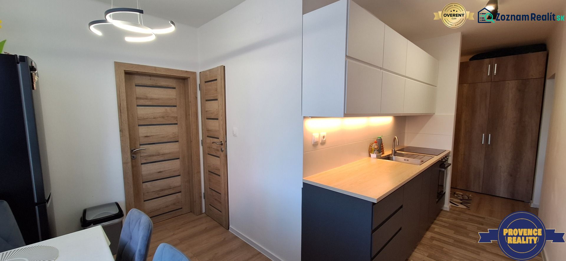 A kitchen in a 3-room apartment with a wooden decor floor and modern lighting.