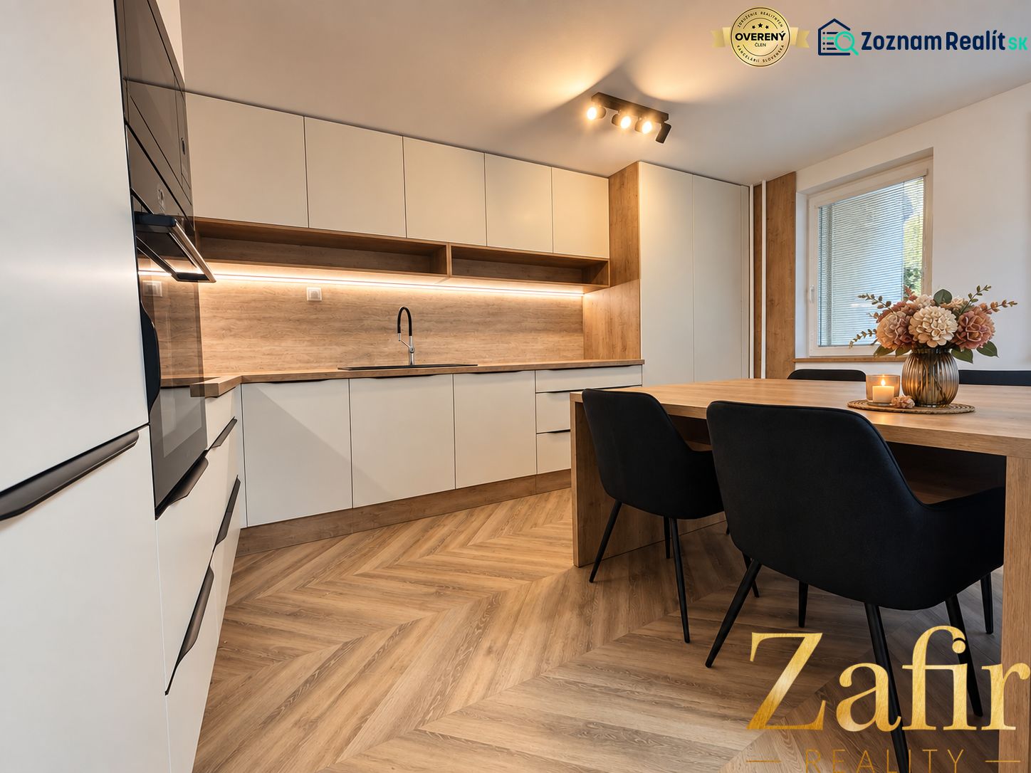 A kitchen in a three-room apartment with a wooden decor floor and a dining table.