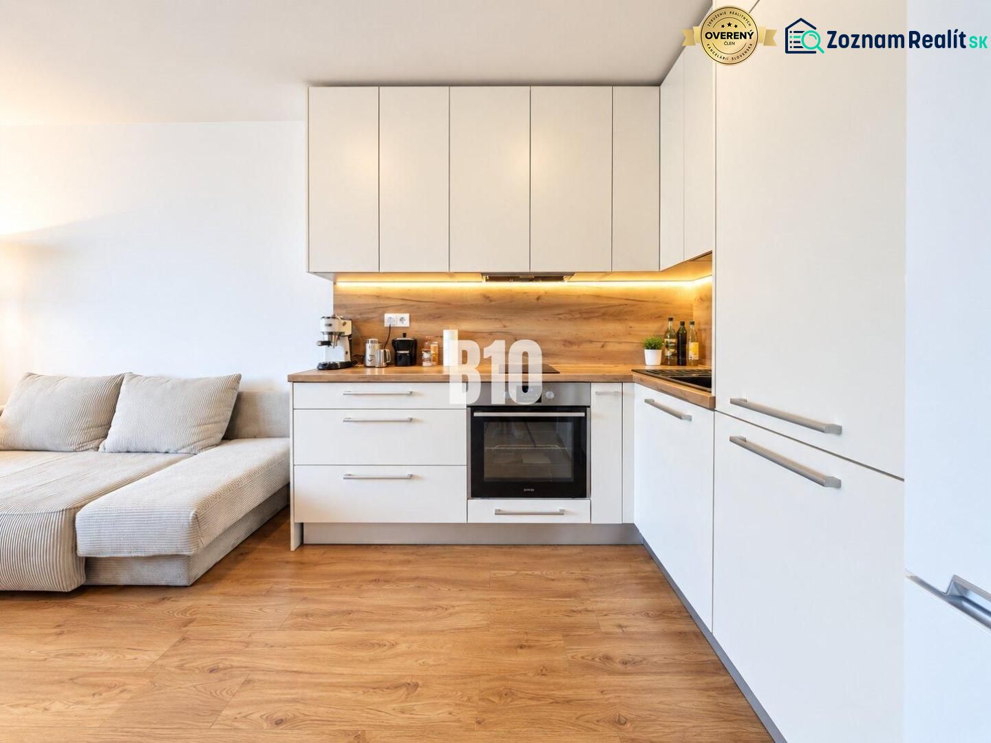 A kitchen in a 2-room apartment with a wood-patterned floor and white cabinets.
