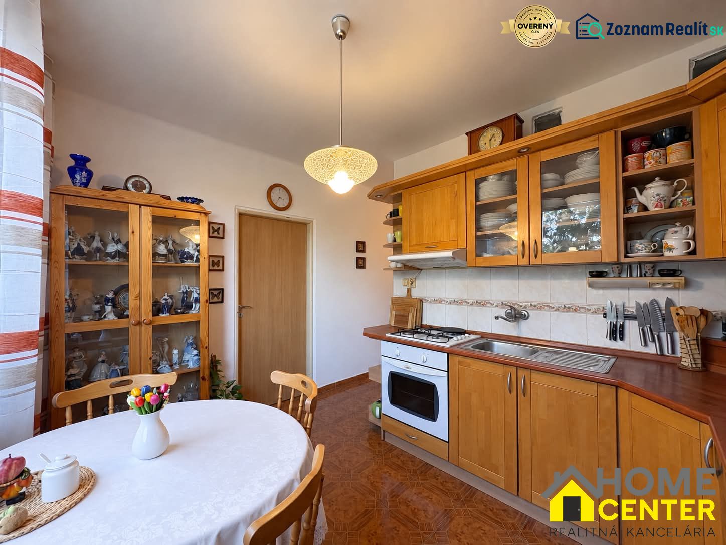 A kitchen in a 3-room apartment with wooden decorations, plates, and a vase with flowers.
