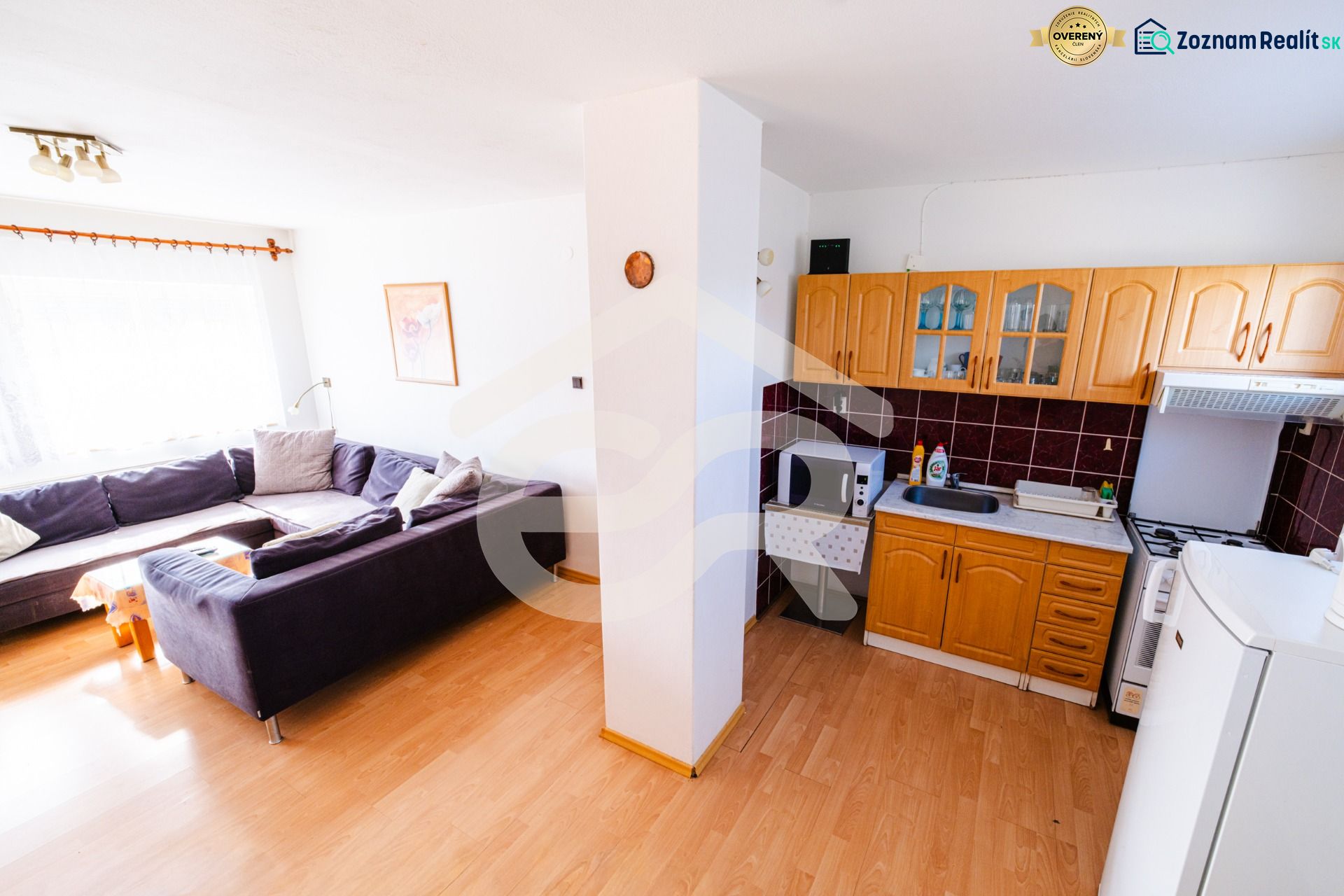 Living room and kitchen in a family house with a corner sofa and kitchen cabinets.