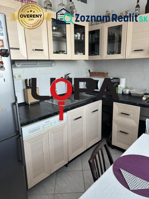 A kitchen in a two-room apartment with wooden decor furniture and light tiles.