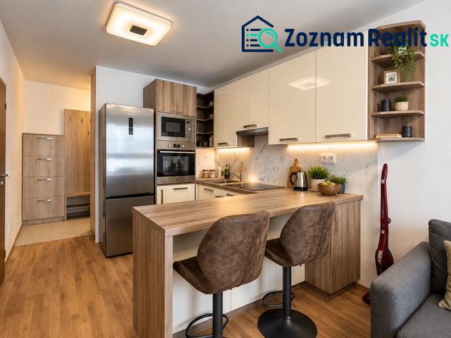 A kitchen in a 2-room apartment with appliances and a wooden decor floor.