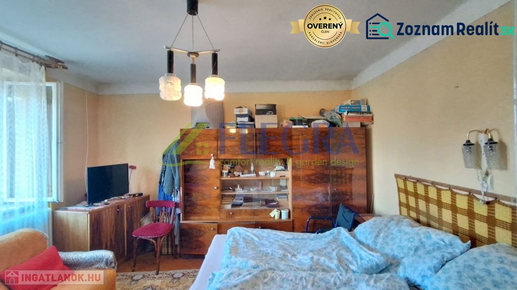 A room in a family house with furniture, a bed, and a television, simple interior.