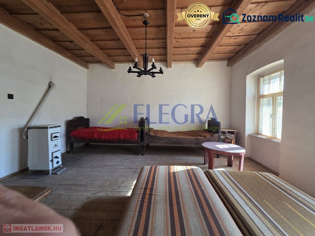 A room in a family house with a wooden ceiling and a tiled stove.