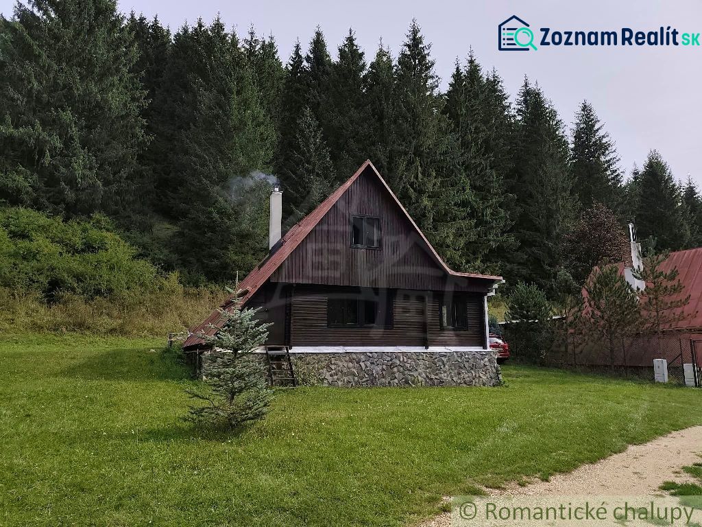 A cottage in Rajecká Lesná amidst forests, surrounded by a green grassy area.