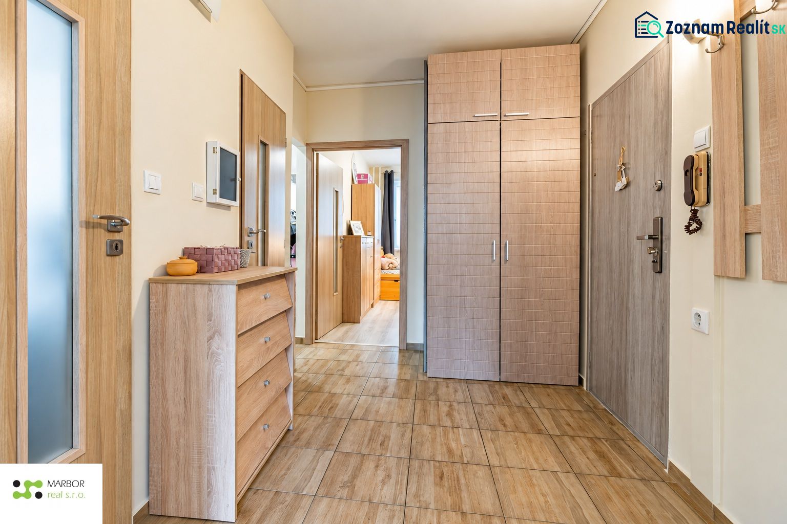 Entrance hall in a 3-room apartment, light wooden doors and floor with wood decor.
