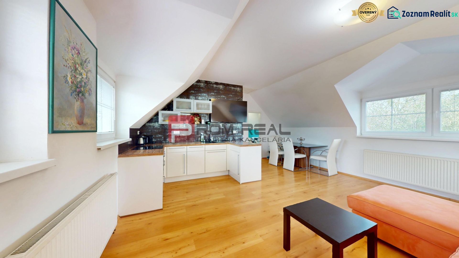 The kitchen with a living room in a 2-room apartment has a wooden decor floor and art on the walls.