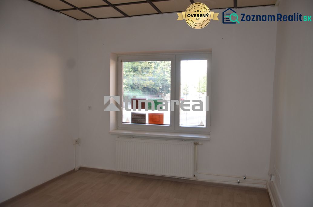 Offices with white walls and a floor with a wooden decor, a window with a radiator is visible.