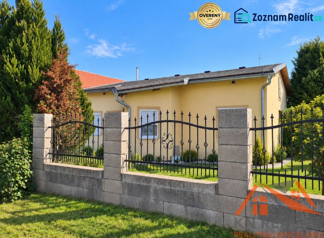 A family house in Martovce with a garden surrounded by green trees and a fence.