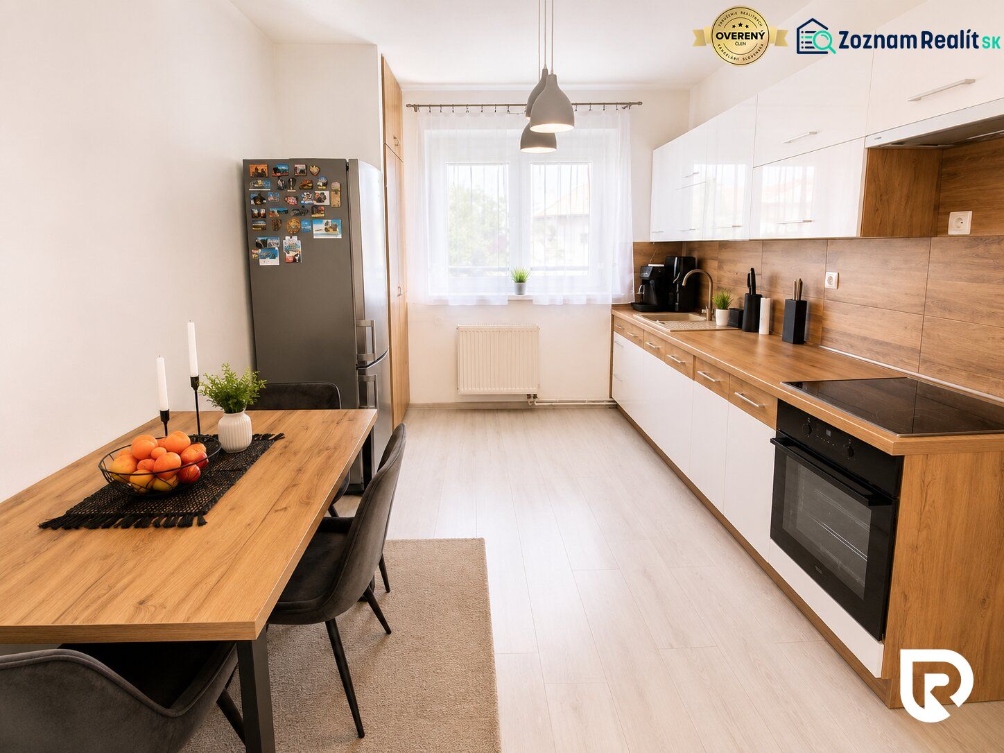A kitchen in a 2-room apartment with a wooden decor floor, a dining table, and appliances.