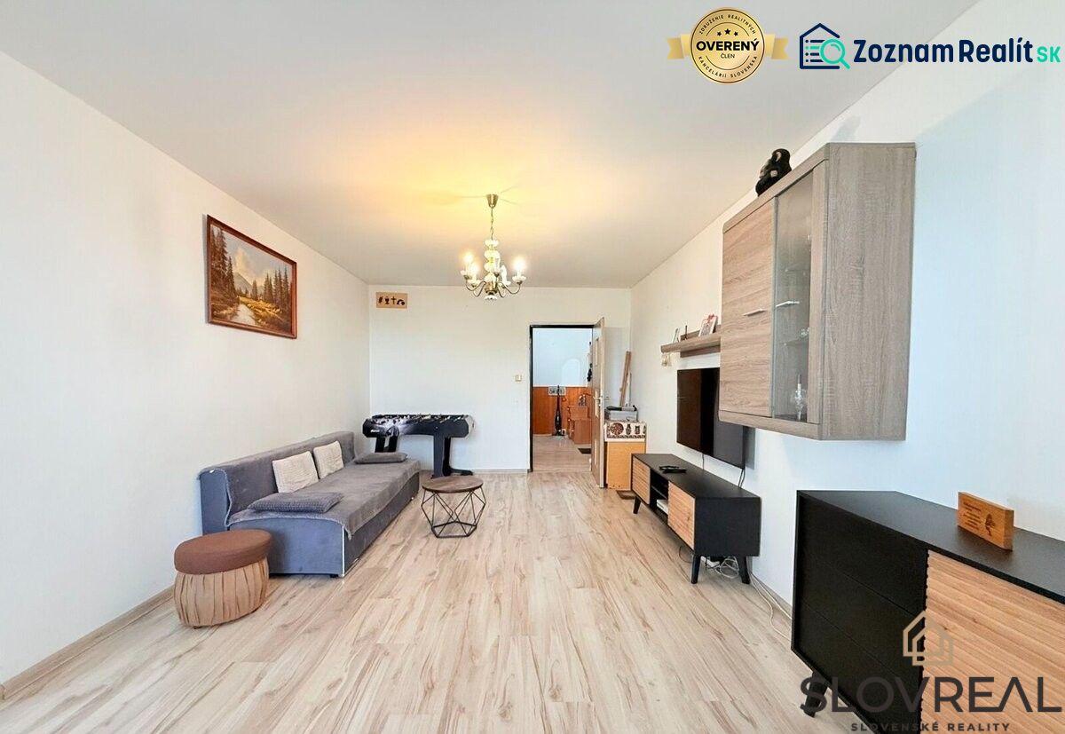 Living room in a 3-room apartment with a wood-patterned floor, gray sofa, and foosball table.