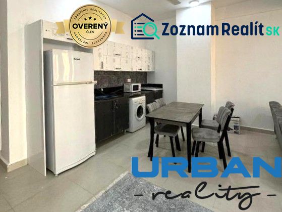 A kitchen in a 2-room apartment with a dining table, refrigerator, and washing machine.