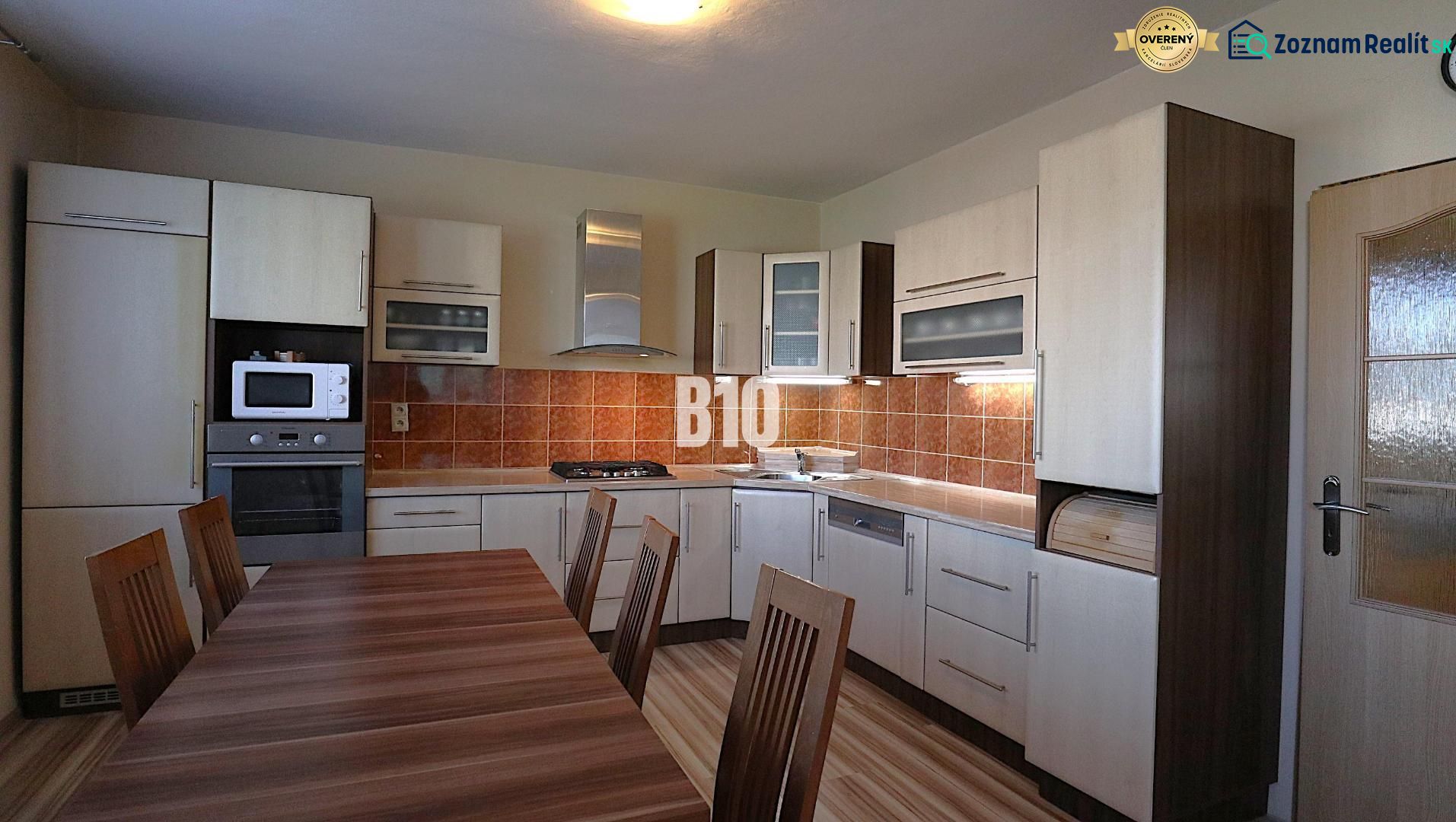 A kitchen in a family house with wooden decor and appliances, featuring a spacious dining table.