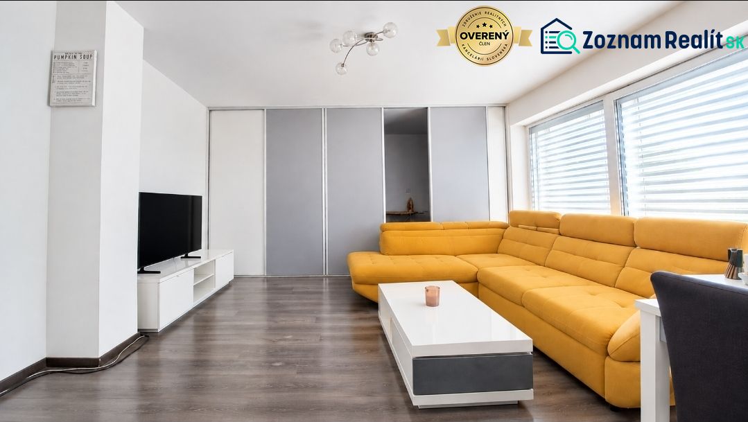 Living room in a family house with a yellow sofa, TV, and a wooden decor floor.