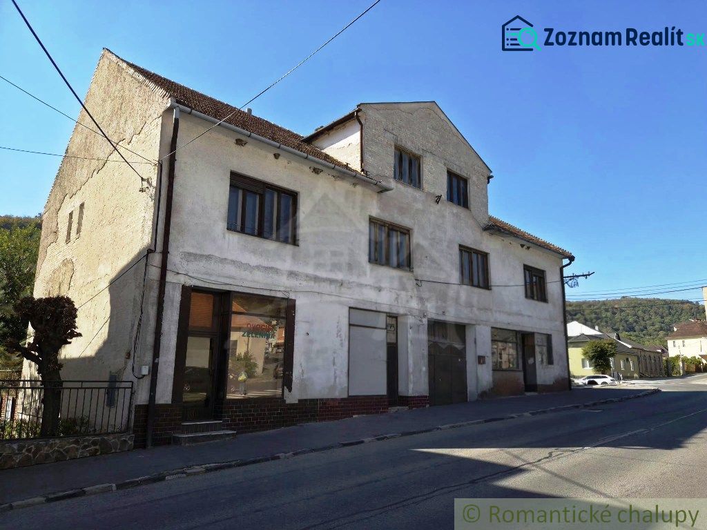 The exterior of a building in Modrý Kameň with commercial spaces, next to the road and nature.