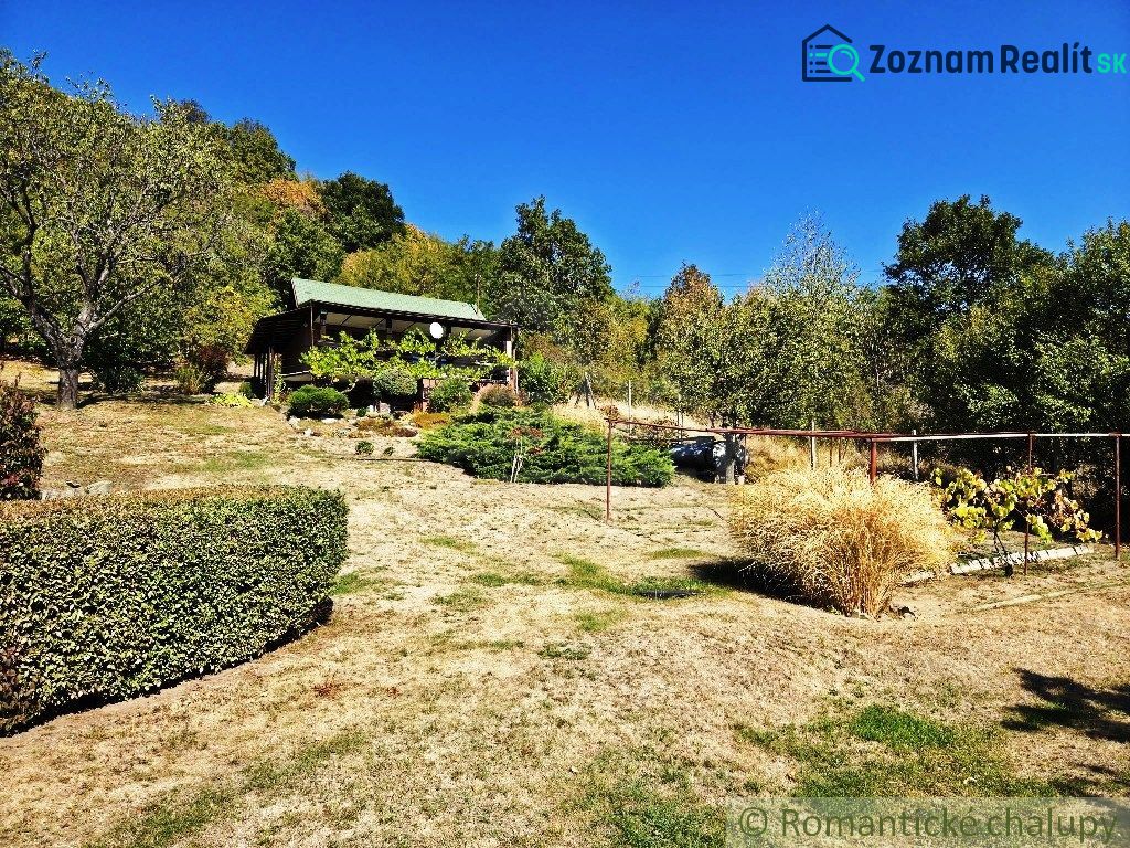 A cottage in Modrý Kameň surrounded by a garden and nature on a sunny day.