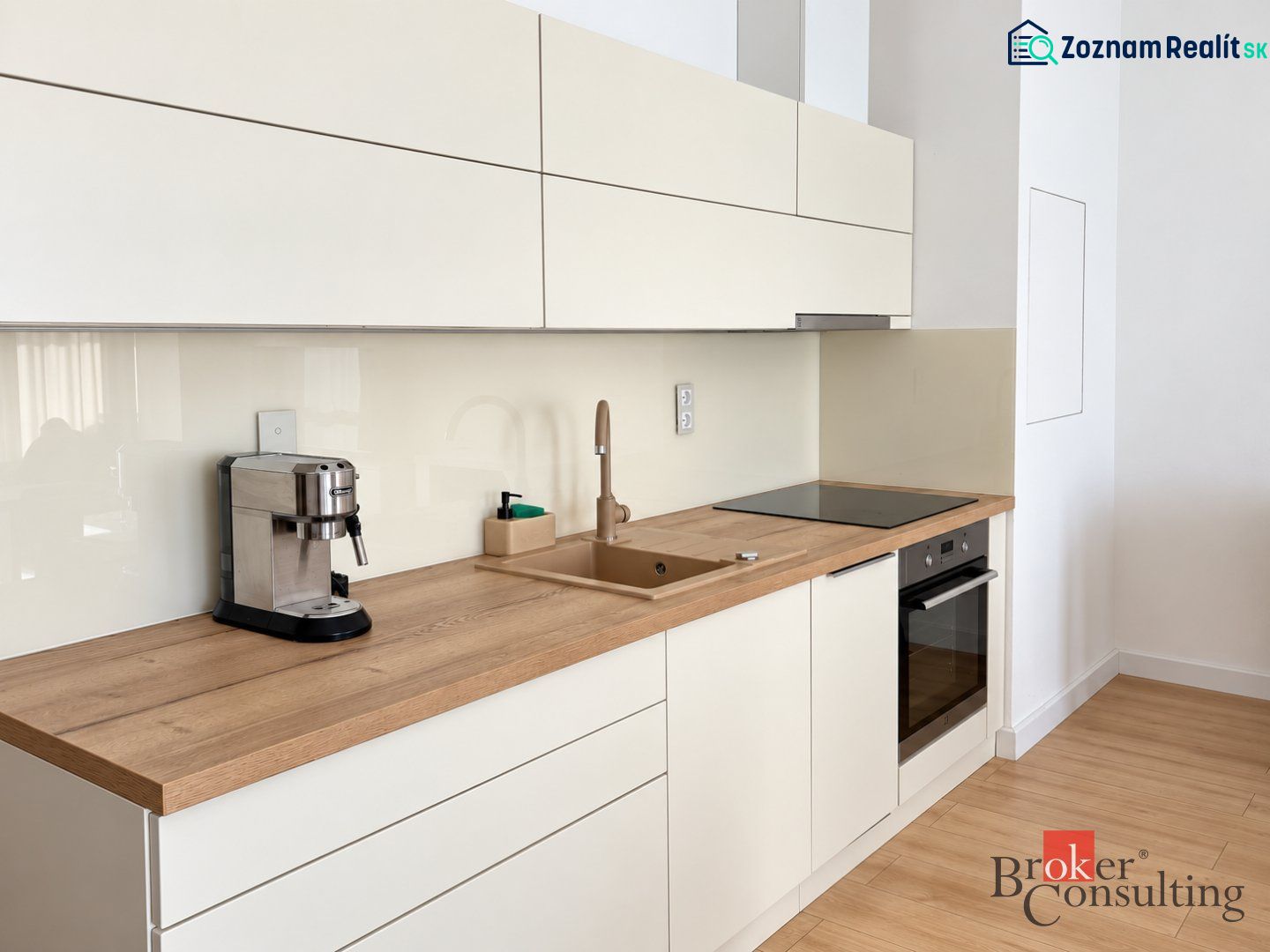 Kitchen in a studio apartment with wood decor flooring, cream cabinets, coffee maker.