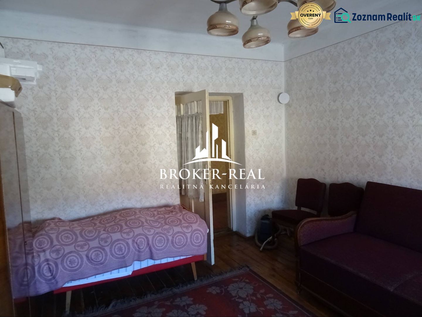 A room with a sofa, bed, and wooden decor flooring in a family house.