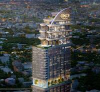 Apartment construction in Chon Buri 20150 with a bright skyscraper during the evening.