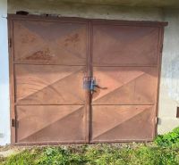 Rusty metal garage doors on Veterná Street in Holíč, surrounded by grass.