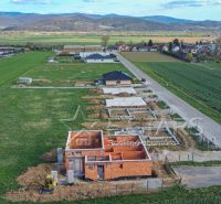 A construction project of a family house in Trenčín surrounded by green fields and a road.