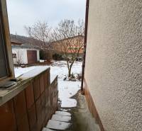 Snowy steps leading to a courtyard with trees in Trenčín on Zamarovce Street.