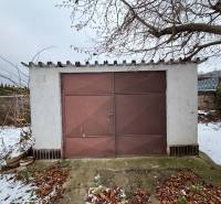 A garage in Zamarovce, Trenčín with an old brown metal entrance and a snow cover.