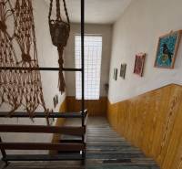 A staircase in a 4-room apartment with wooden paneling, hanging decorations, and paintings.