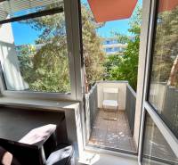 A balcony of a 2-room apartment with a view of greenery and surrounding architecture.