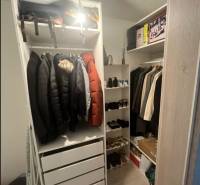 A cozy wardrobe with hangers and shelves in a 2-room apartment, full of clothes and shoes.