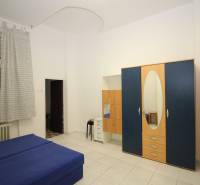 A bedroom with a blue sofa, a wardrobe, and a built-in mirror in a studio apartment.