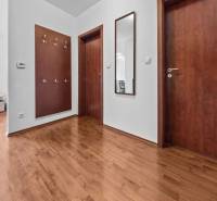 A hallway with wooden doors and flooring, coat racks, and a mirror in a two-room apartment.
