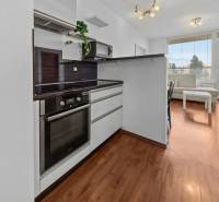 A kitchen with a wooden floor and a living area in a two-room apartment.