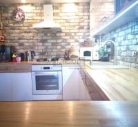 A kitchen in a 3-room apartment with brick cladding and a wooden countertop.