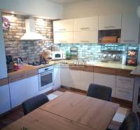 A kitchen in a 3-room apartment with brick cladding and a dining table.