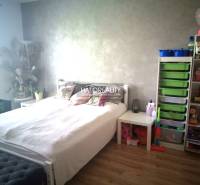 Bright bedroom in a 3-room apartment with a bed, storage space, and children's toys.