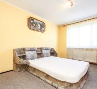A bedroom in a 3-room apartment with a painting, a sofa, and a window with curtains.