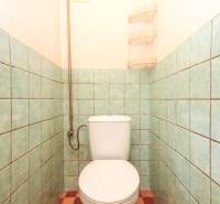 Bathroom in a 3-room apartment with a toilet, tiling, and practical shelves.