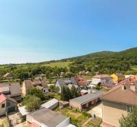 View of houses and greenery on Cementárska Street in Horné Srnie, with a panorama of the surrounding hills.