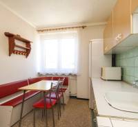 A kitchen in a 3-room apartment with a corner bench, table, and light cabinets.