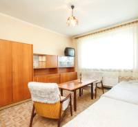 Living room with wooden furniture, carpet, and a window with white curtains in a three-room apartment.