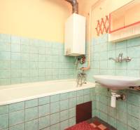 A bathroom with a bathtub and a sink in a 3-room apartment, tiled with blue tiles.