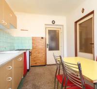 Kitchen of a 3-room apartment with a dining table, cabinets, and a sink.