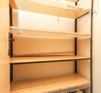 Shelf unit in the pantry of a 3-room apartment with various items and decorations.