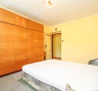 A bedroom in a 3-room apartment with a wooden wardrobe and bed.