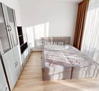 A bright bedroom with a gray wardrobe and bed in a 2-room apartment.