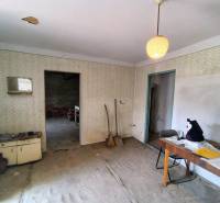 A room in a family house with worn-out furniture and cracked walls.
