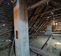 An attic in a family house with visible wooden beams and a brick wall.