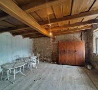 A room in a family house with a wooden ceiling, old furniture, and a brick wall.